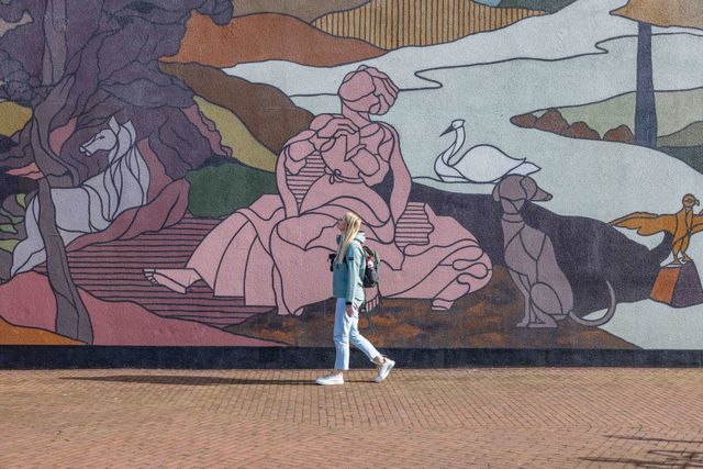 Meisje voor de mural op de bibliotheekmuur in Helmond