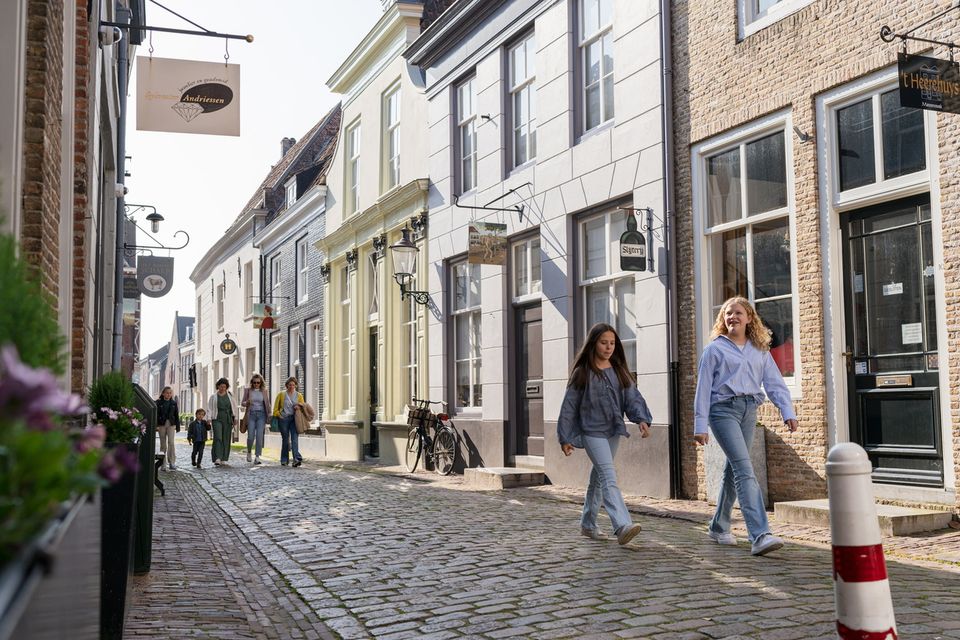 Een groepje volwassenen en kinderen loopt door de straatjes van vestingstad Heusden