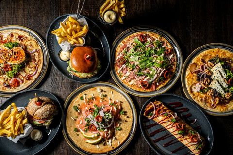 Een tafel vol met gerechten waaronder pannenkoeken en burgers.