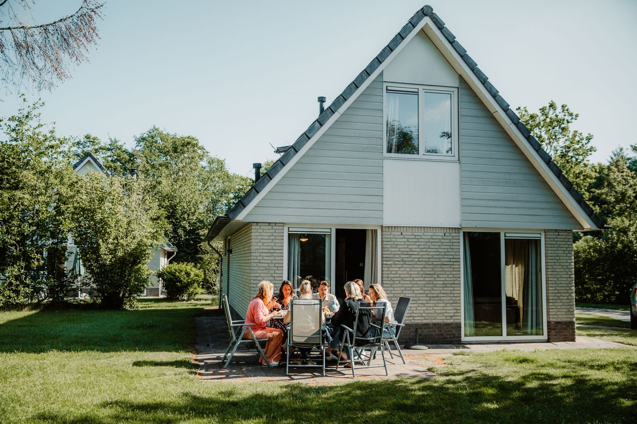 Een groep vriendinnen ontbijt samen op het terras van een vakantiebungalow bij Landgoed Ruwinkel. De zonnige foto benadrukt gezellig samenzijn en ontspannen verblijven in een groene omgeving.
