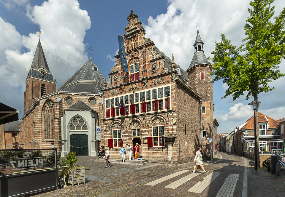Voorgevel van het Stadsmuseum Woerden in het historische Oude Raadhuis met rode luiken en bezoekers op het plein, Groene Hart.