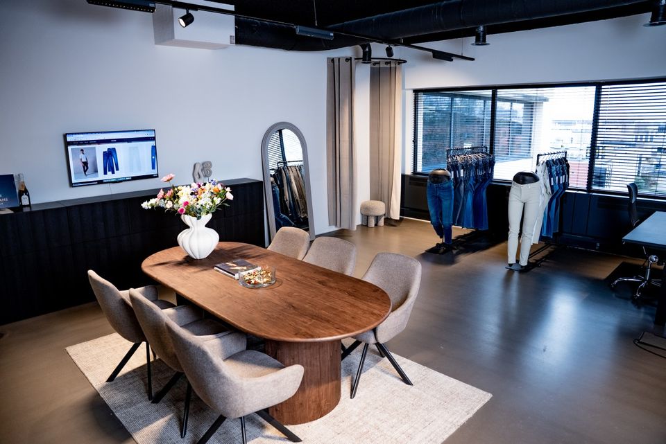 Jeanswinkel Busker Jeans in Woerden, Groene Hart, interieur van de winkelruimte met centrale tafel en stoelen, paskamers en presentatie van jeanskleding.