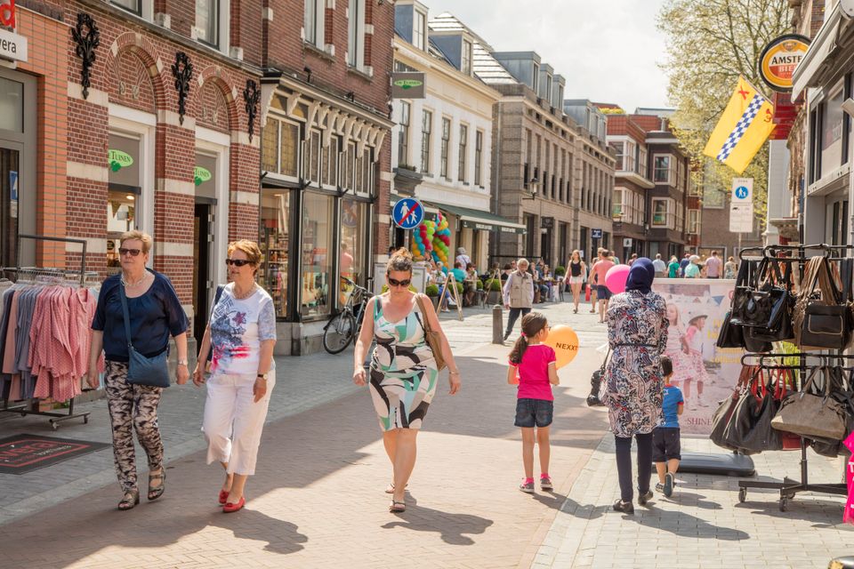 Bezoekers winkelen in het centrum van Woerden tussen historische gevels, winkels en horeca op een zonnige dag