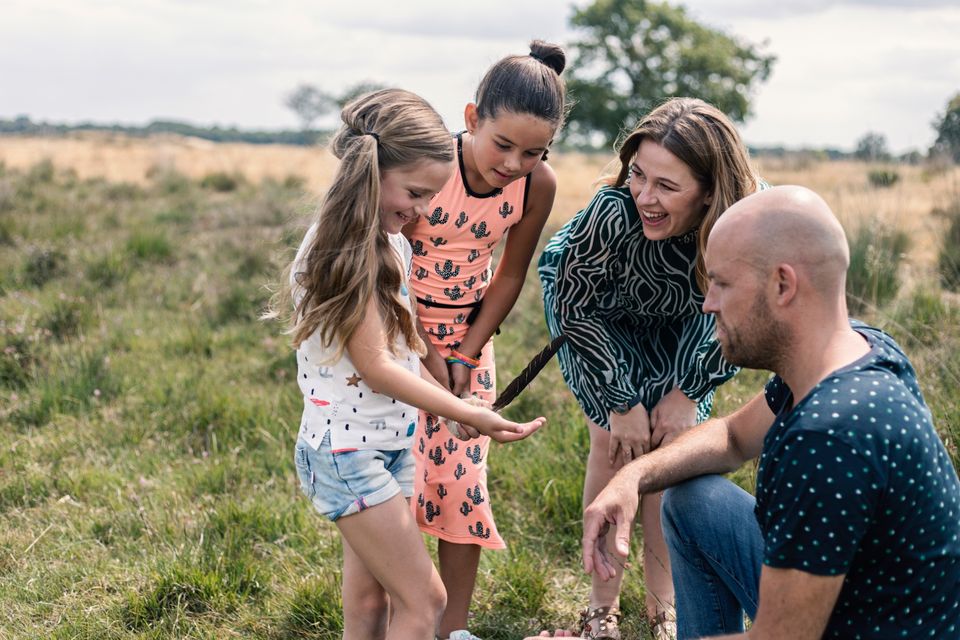 Een meisje laat aan haar ouders en zus een veer zien die ze tijdens de wandeling gevonden heeft.