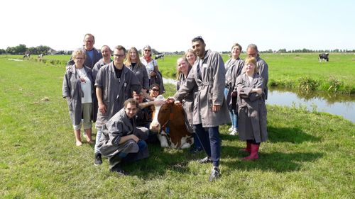 Personeel van Kastanje Hoeve Beets bij een koe in de wei