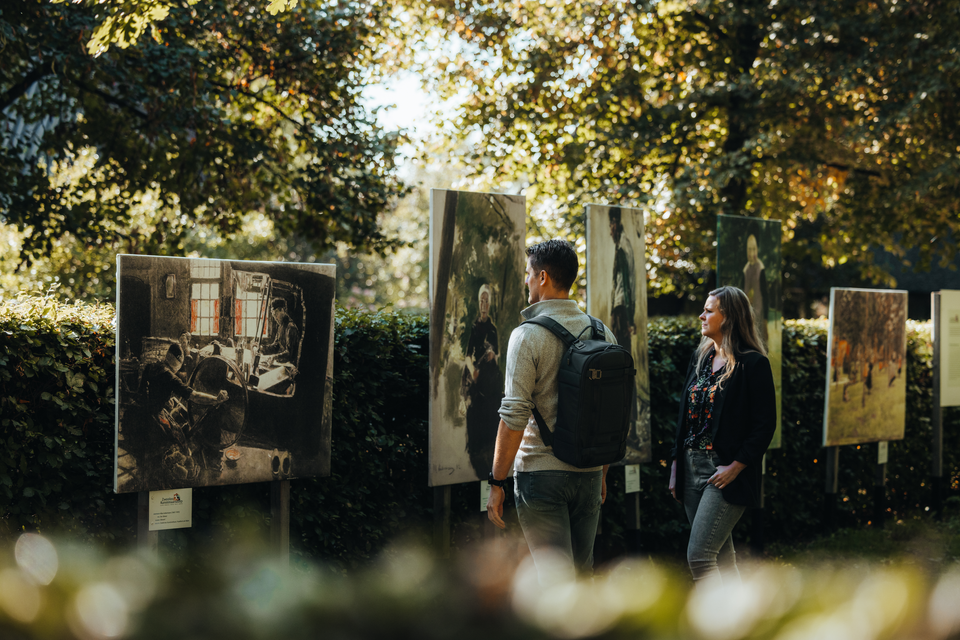Een man en een vrouw lopen langs reproducties van schilderijen van Van Gogh die in de buitenlucht in Zweeloo staan.
