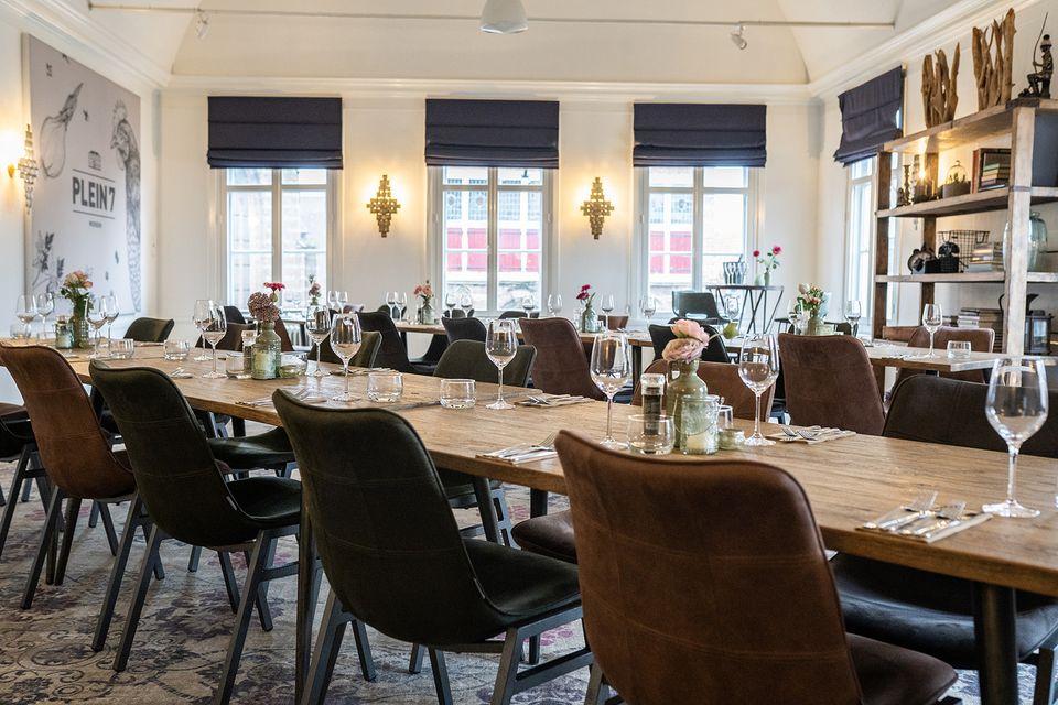 Dineropstelling met lange tafels en gedekte glazen in de vergaderruimte van Plein 7 in Woerden.