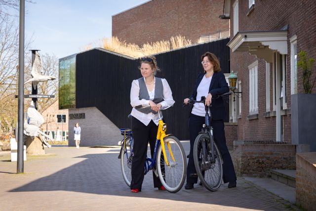Twee fietsers staan op de stoep voor Singer Laren.