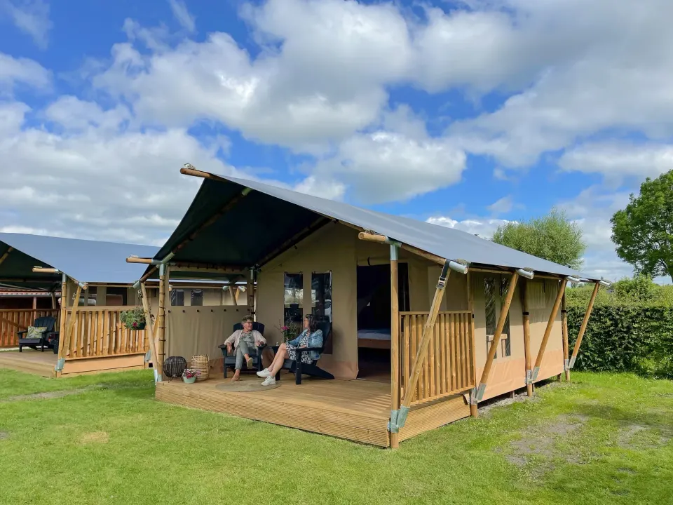 Een safaritent met twee mensen op de veranda bij Watersportcamping De Bearshoeke in Oudega.