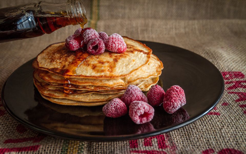 Stapel pannenkoeken met verse frambozen en stroop.