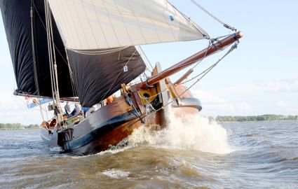 Het skûtsje van Heeg die tegen de wind in vaart waardoor het skûtsje scheef begin te varen.