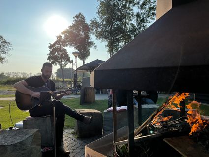 Man op gitaar bij kampvuur