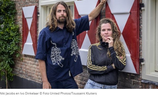 Een man en een vrouw leunend tegen een gebouw