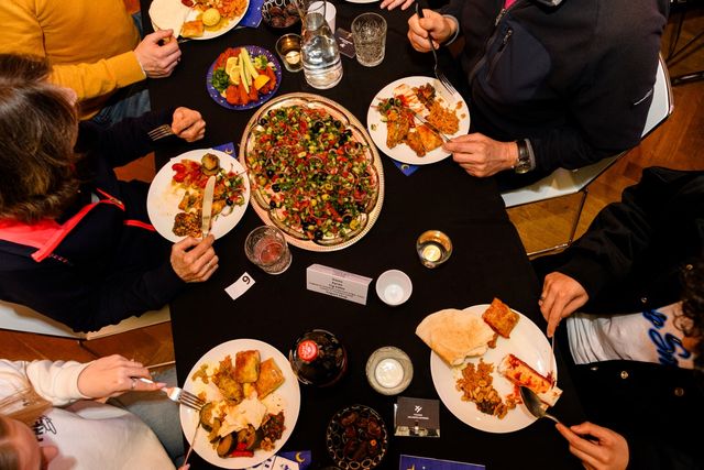 Iftar in Museum Hilversum, een tafel van bovenaf gefotografeerd waar mensen deelnemen aan de maaltijd