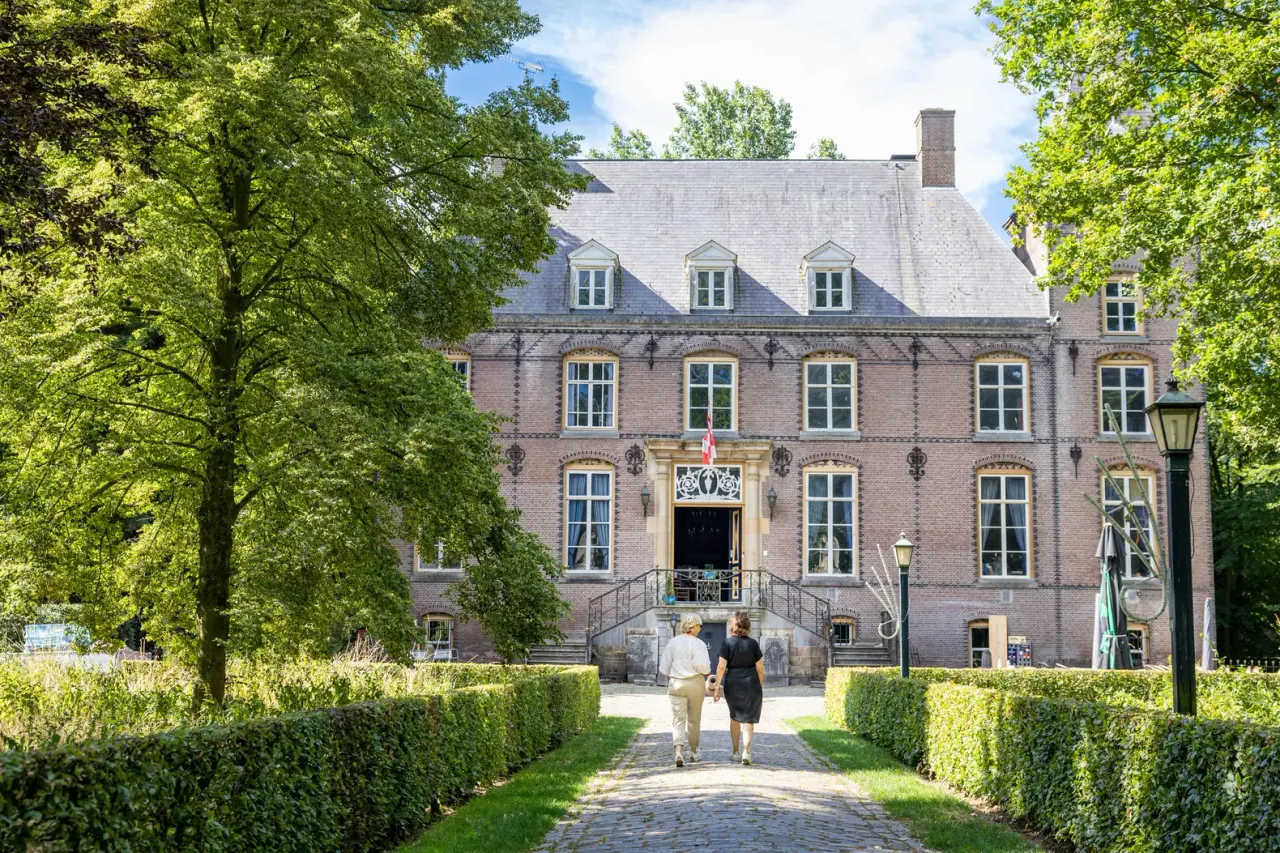 Twee wandelaars lopen op de oprijlaan van Kasteel Nemerlaer Haaren