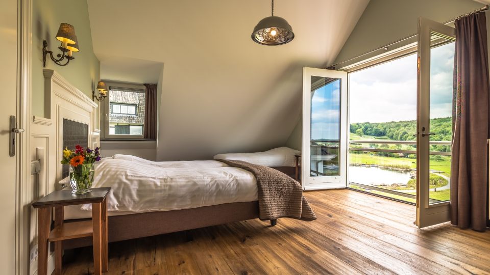 Chambre spacieuse et atmosphérique de la Villa Schweiberg avec une vue imprenable sur le paysage vallonné.