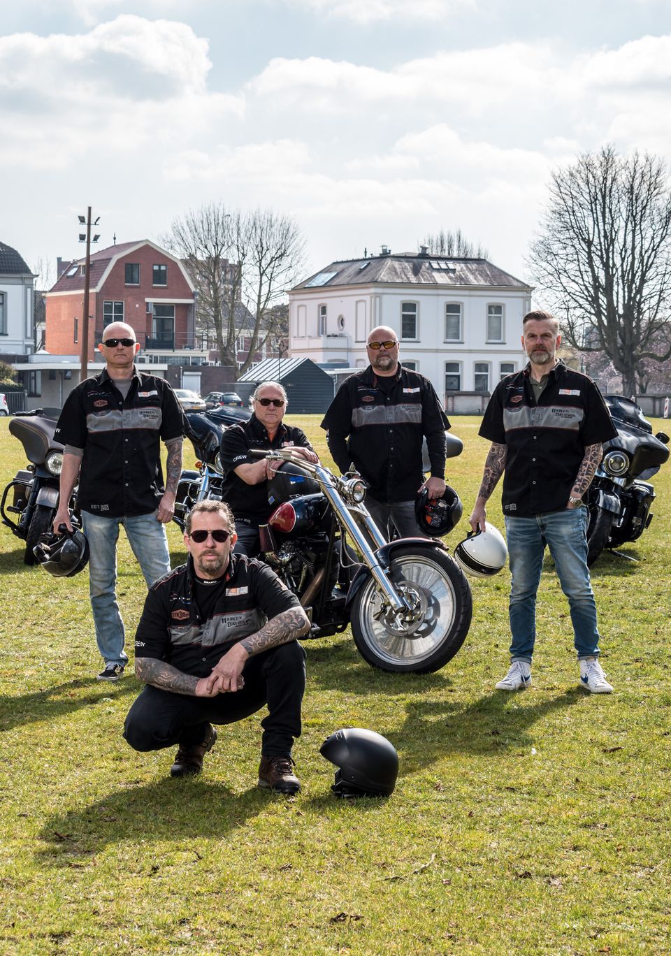 Groep Harley-Davidson-rijders poseert met motoren op het Exercitieveld in Woerden tijdens Harleydag, gekleed in bijpassende clubkleding en met motorhelmen.