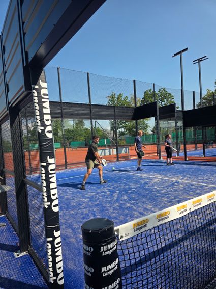 Padelbaan bij VEP Tennis & Padel, met drie spelers tijdens een potje padel op een blauwe buitenbaan met glazen wanden.
