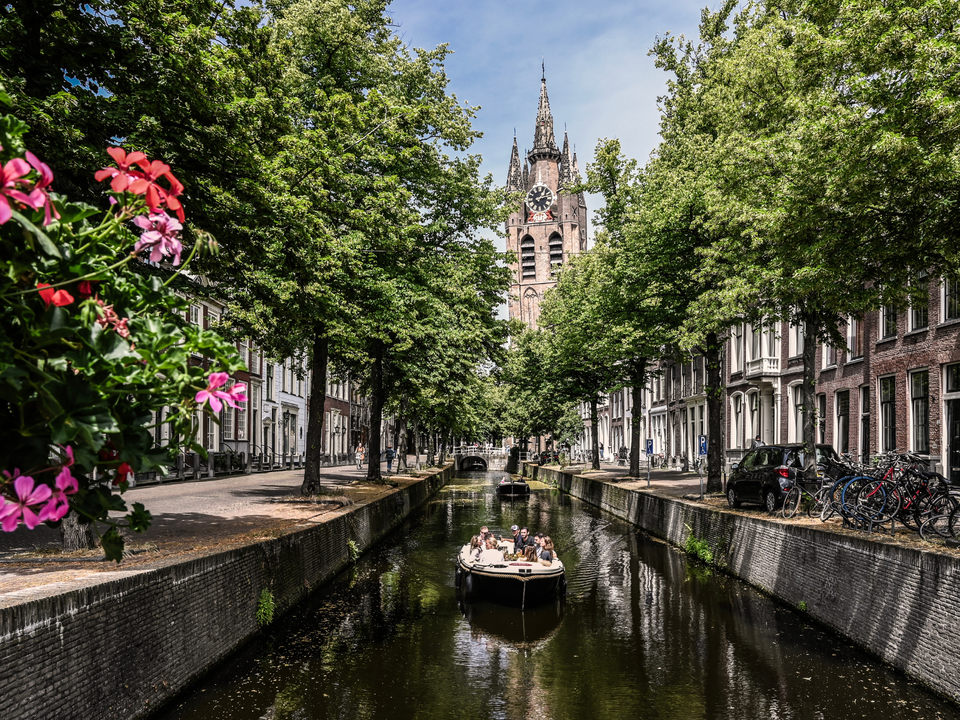 Zomerse dag in Delft met een bootje op de grachten en uitzicht op de Oude Kerk