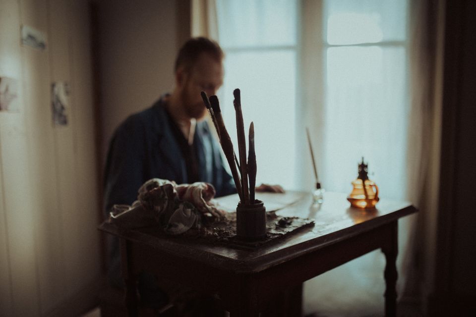 Iemand zit aan en tafeltje te schilderen in de kamer van Van Gogh