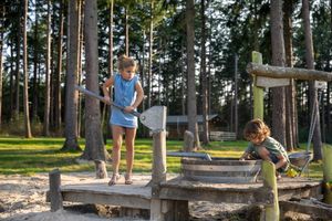 Kinderen spelen met een waterpomp op een camping in Drenthe.