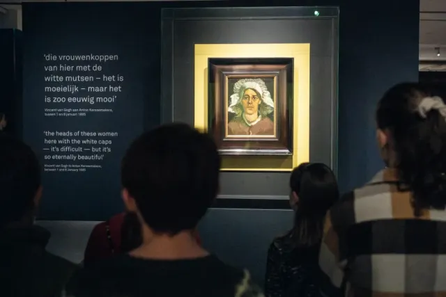 Kinderen staan in het museum en kijken naar het schilderij 'Kop van een vrouw' (Gordina) van Vincent van Gogh.
