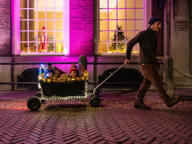 Vader met twee kinderen in een bolderkar met kerstmutsjes