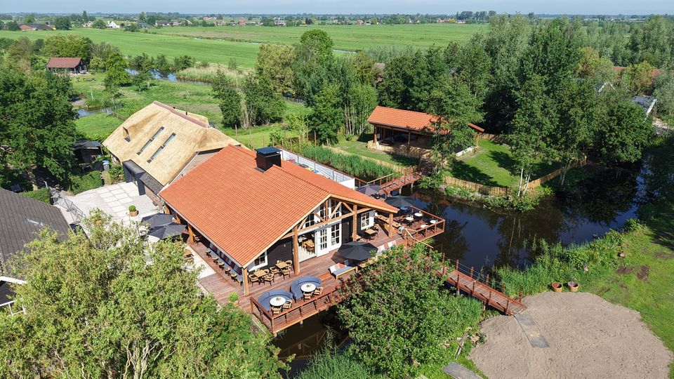 Restaurant De Oortjeshoeve in Kamerik, Groene Hart. Luchtfoto van restaurant met terras aan het water, rieten dak, houten veranda en uitzicht over het polderlandschap van het Groene Hart.