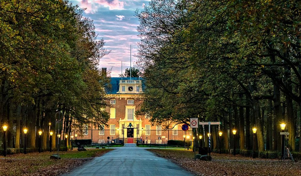 De zon gaat onder achter Slot Zeist en zorgt voor een lila gekleurde lucht