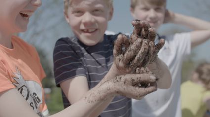 Drie jongens die bloembollen aan het maken zijn en vieze handen hebben