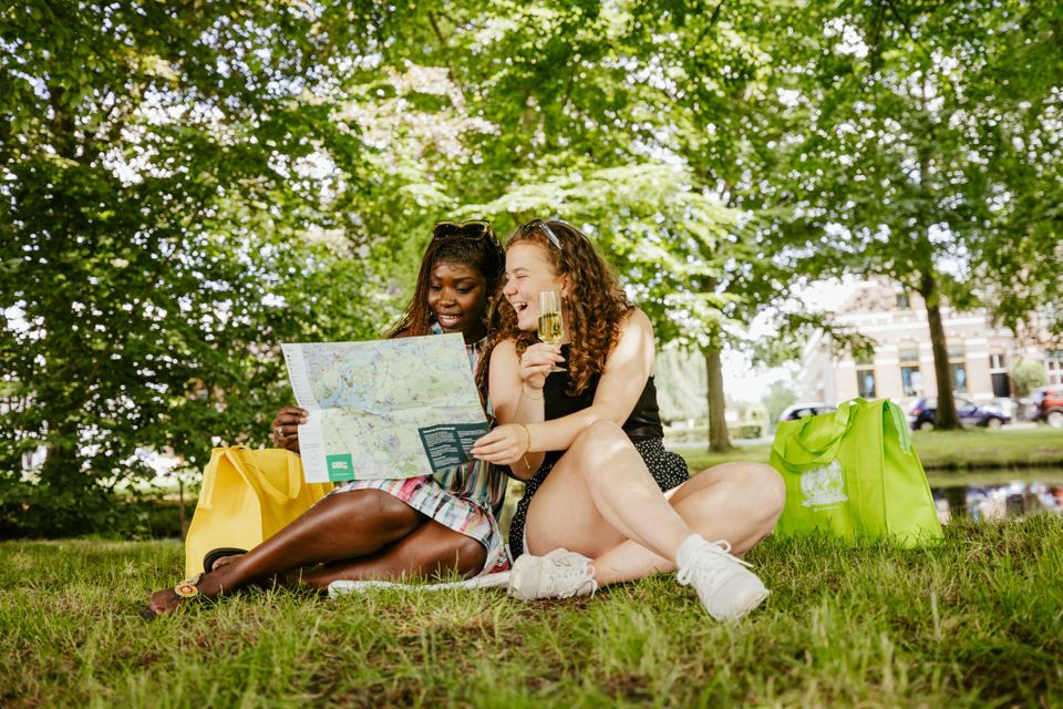 Twee dames zitten op het gras en kijken op een kaart