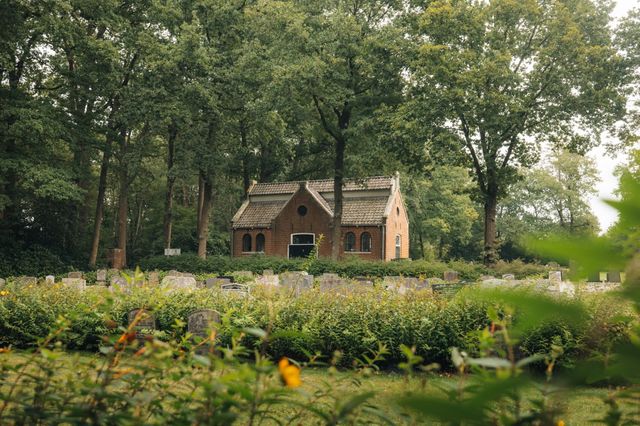 Begraafplaats met oude graven en een gebouw op de achtergrond.