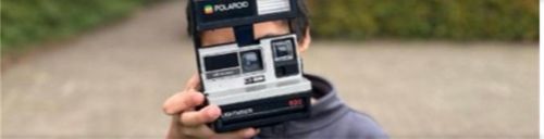 iemand die een polaroid camera vasthoudt