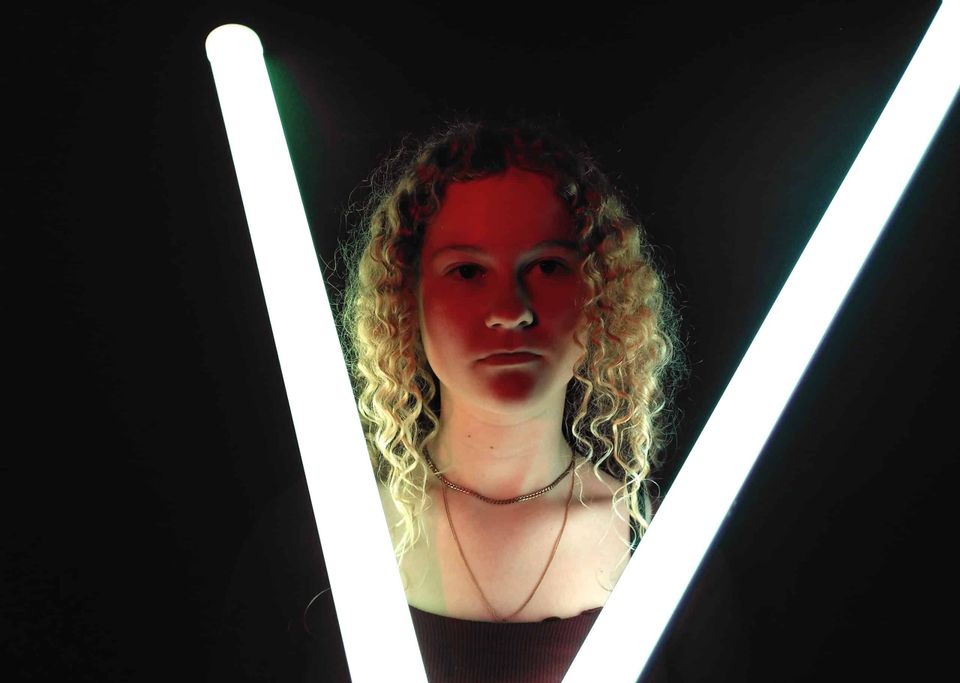 Jongere tussen lichtbuizen tijdens een creatieve activiteit in Het Klooster in Woerden.