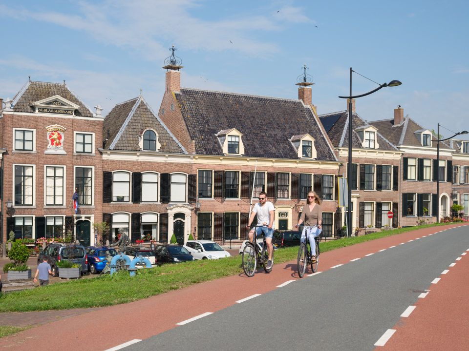 Een man en een vrouw fietsen in de zomer door Ameide over de Lekdijk.