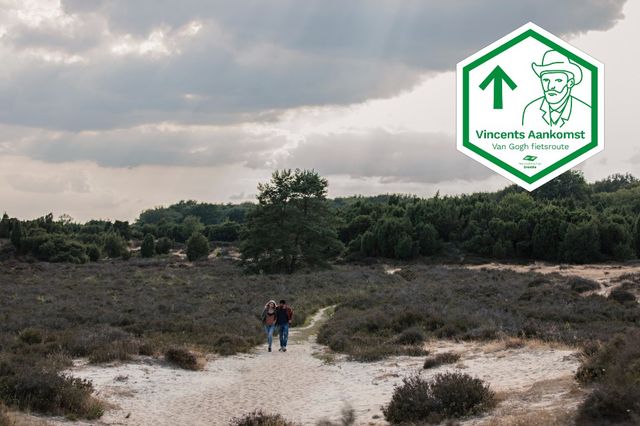 Een man en een vrouw wandelen over een zandverstuivingen op het Mantingerzand