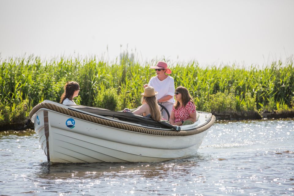 Vier vrouwen varen gezellig in een sloep door Zuidwest Friesland met op de achtergrond groen gras.