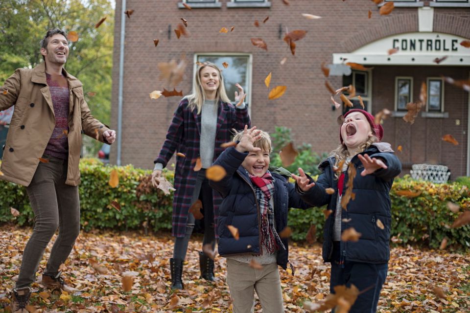 Een gezin gooit met herfstbladeren door de lucht.