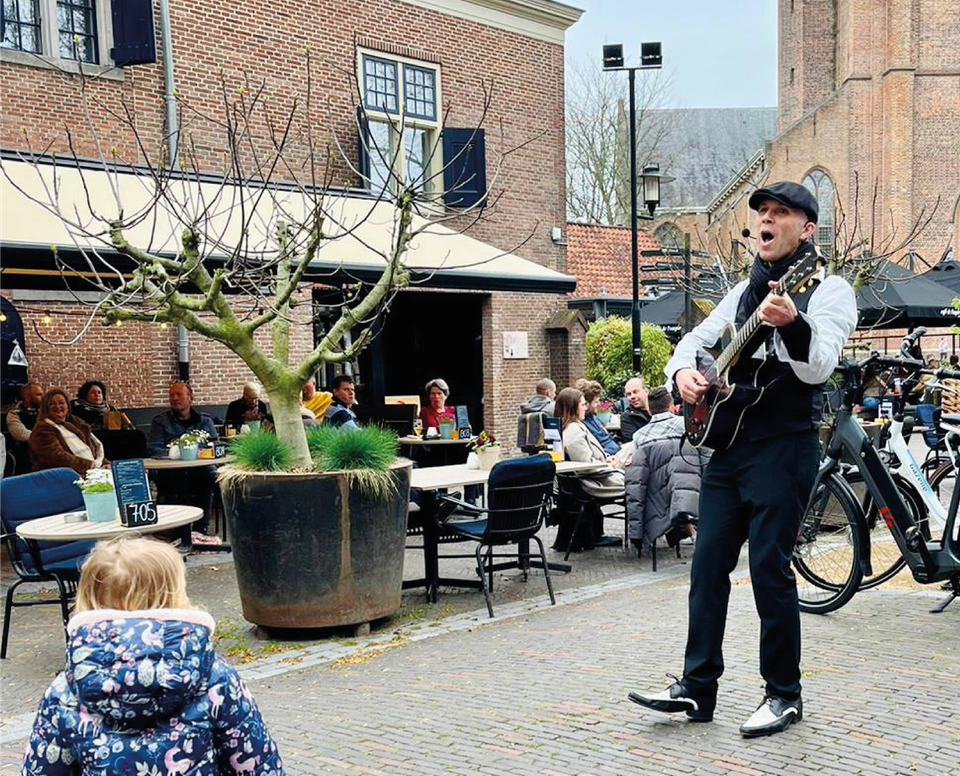 Evenement Tour De Terras La La Lente in Woerden, Groene Hart, live muziek met straatmuzikant op gitaar tussen volle terrassen en publiek in het historische centrum.