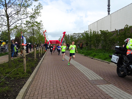 Hardloopevenement Weteringloop in Kamerik, Groene Hart, finishstraat met jonge deelnemers die sprinten richting de RegioBank-finishboog, toeschouwers langs het parcours en verkeersbegeleiding langs de weg.