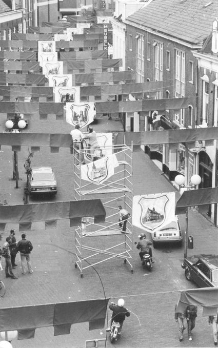 Beschrijving: Het bevestigen van een aantal guirlandes met afbeeldingen ter gelegenheid van de Vierdaagsefeesten
Datering: 24/6/1981