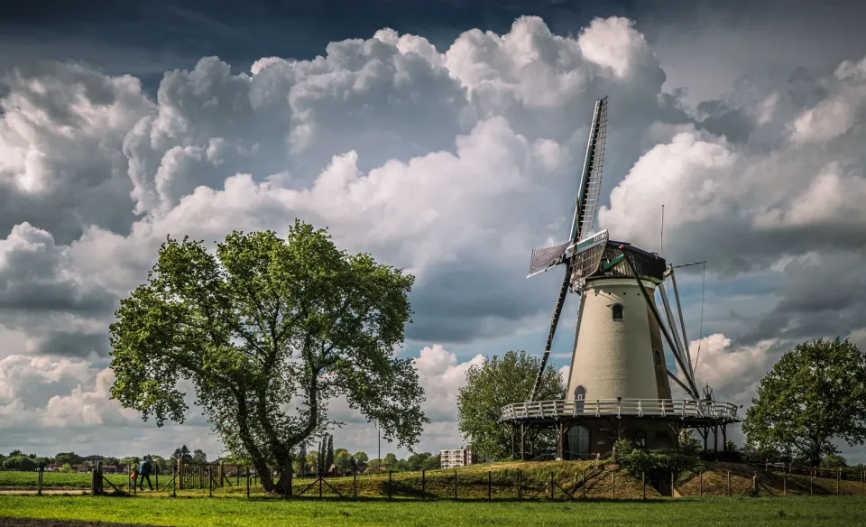Korenmolen De Windhond in Soest staat in een groen landschap onder een bewolkte lucht.