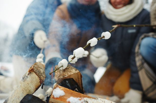 Vrienden roosteren marshmallows bij kampvuur.