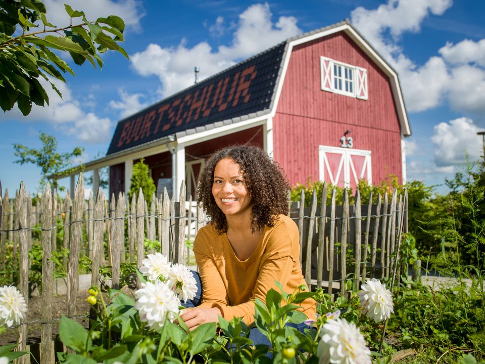 Vrouw tussen de bloemen voor de buurtschuur in Nobelhorst in Almere, Flevoland