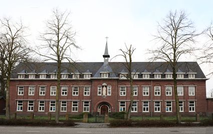 breed groot gebouw met torentje en groot wit beeld boven de voordeur