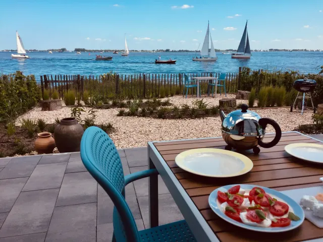 Het terras met uitzicht op allemaal zeilbootjes op het Sneekermeer bij vakantieappartement Lake House Sneekermeer in Offingawier.