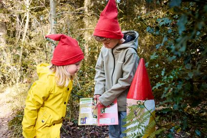 Twee kindjes met kaboutermutsen op, 1 wijst iets aan op een kaart.