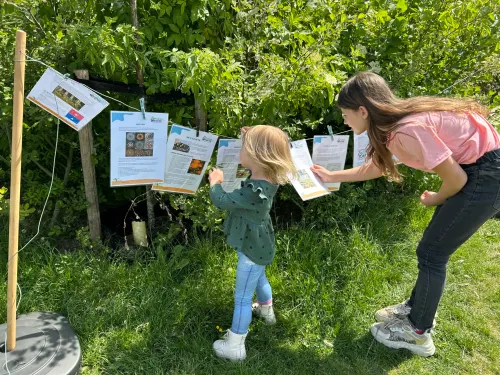Twee kinderen kijken naar bedrukte papieren aan een waslijn