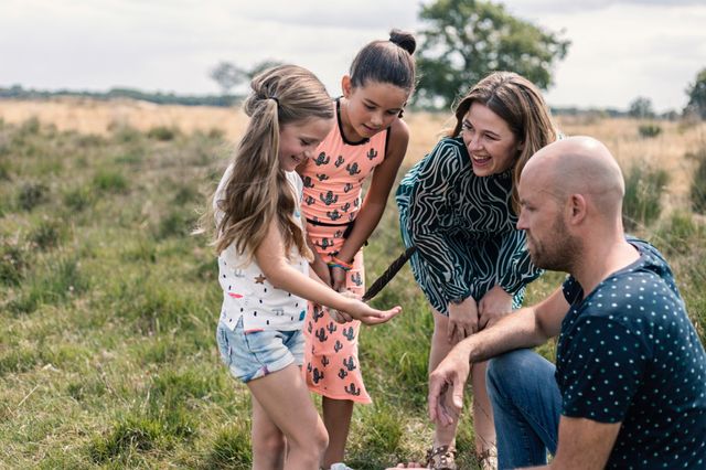 Een meisje laat aan haar ouders en zus een veer zien die ze tijdens de wandeling gevonden heeft.
