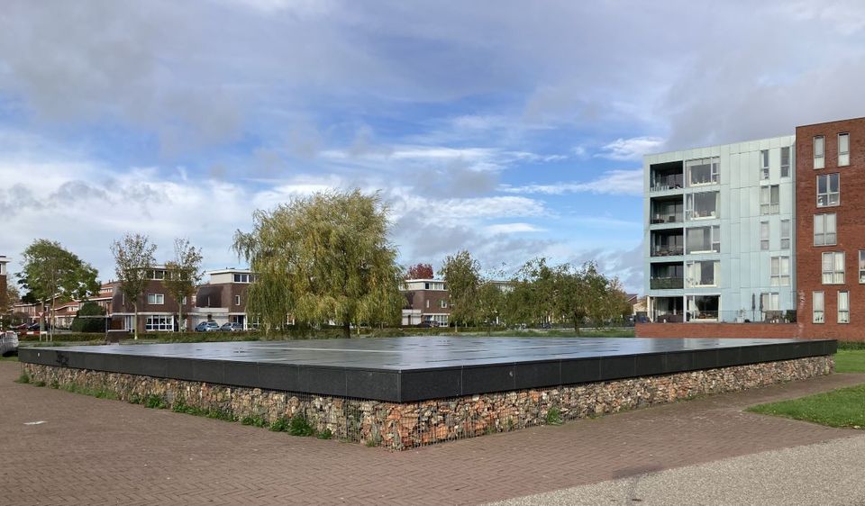 Van steen en resten van de archeologische opgravingen in een opstaand plateau gecreëerd, met stalen korf om het puin.